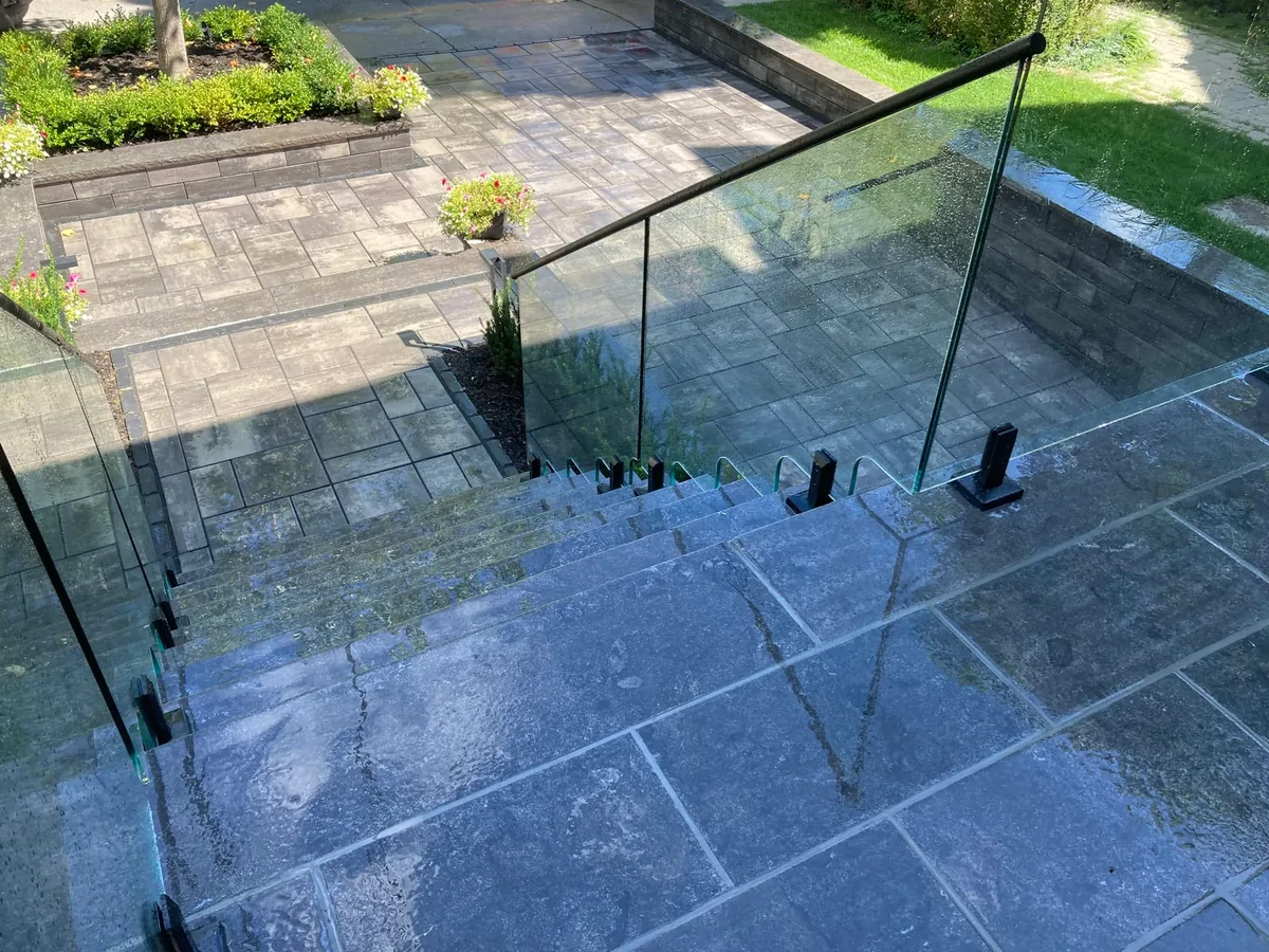 An elevated view looking down at stone steps leading to a lower patio and garden bed.