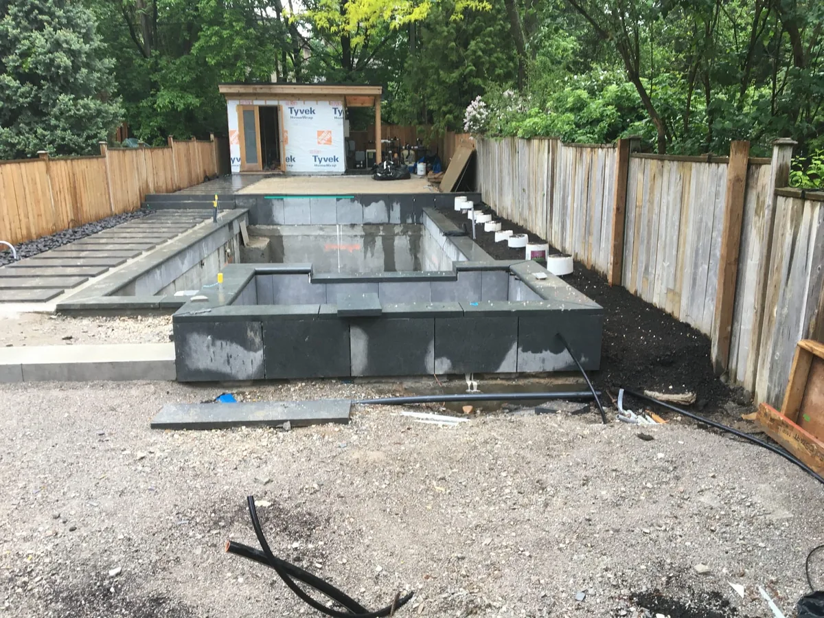 A wide view of the same backyard pool wall on a wet, overcast day.
