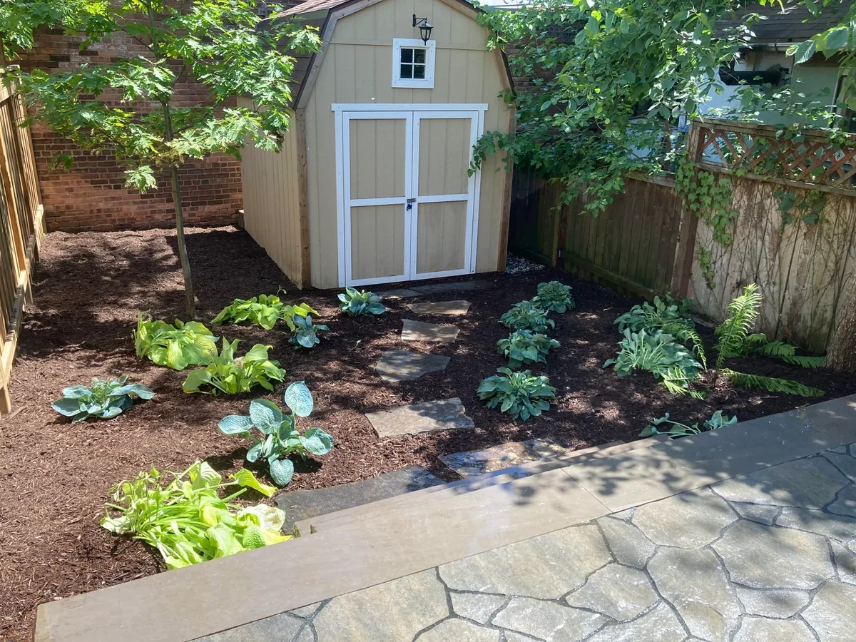 A closer view of the shed with white trim and the planted garden bed.