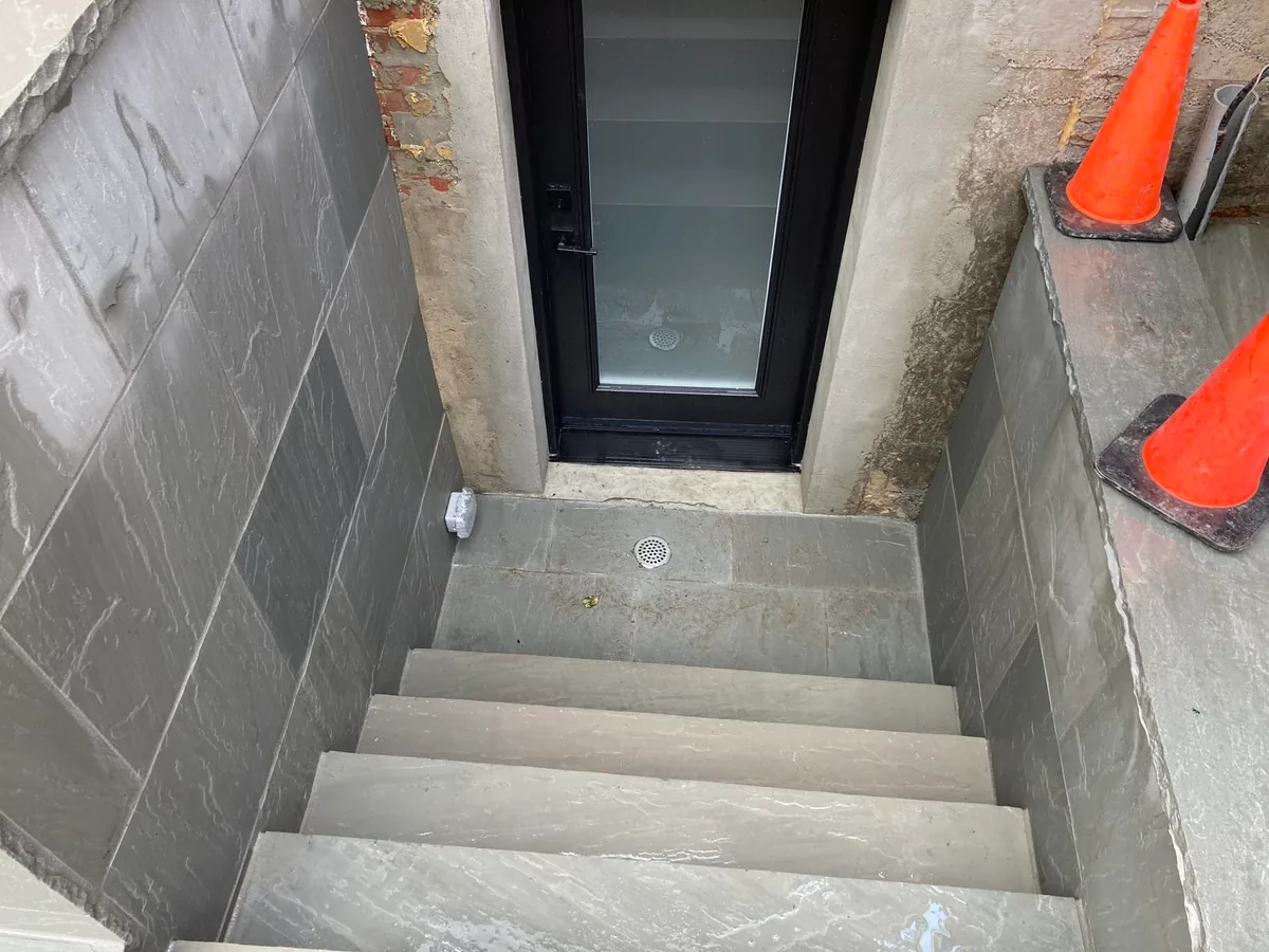 A close-up of stairwell steps down beside a door and a cone.