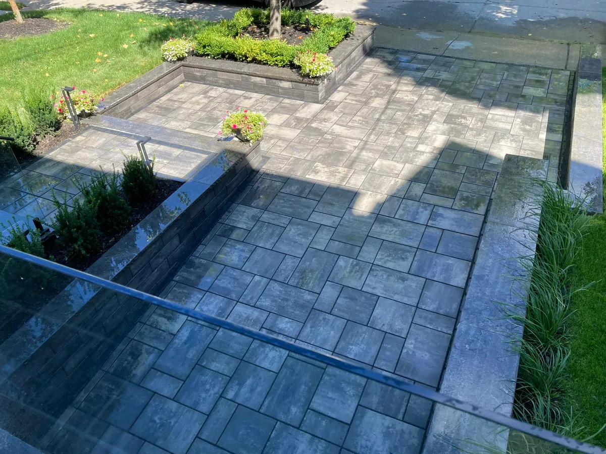An aerial view of the lower stone patio bordered by a garden bed with shrubs and flowers.