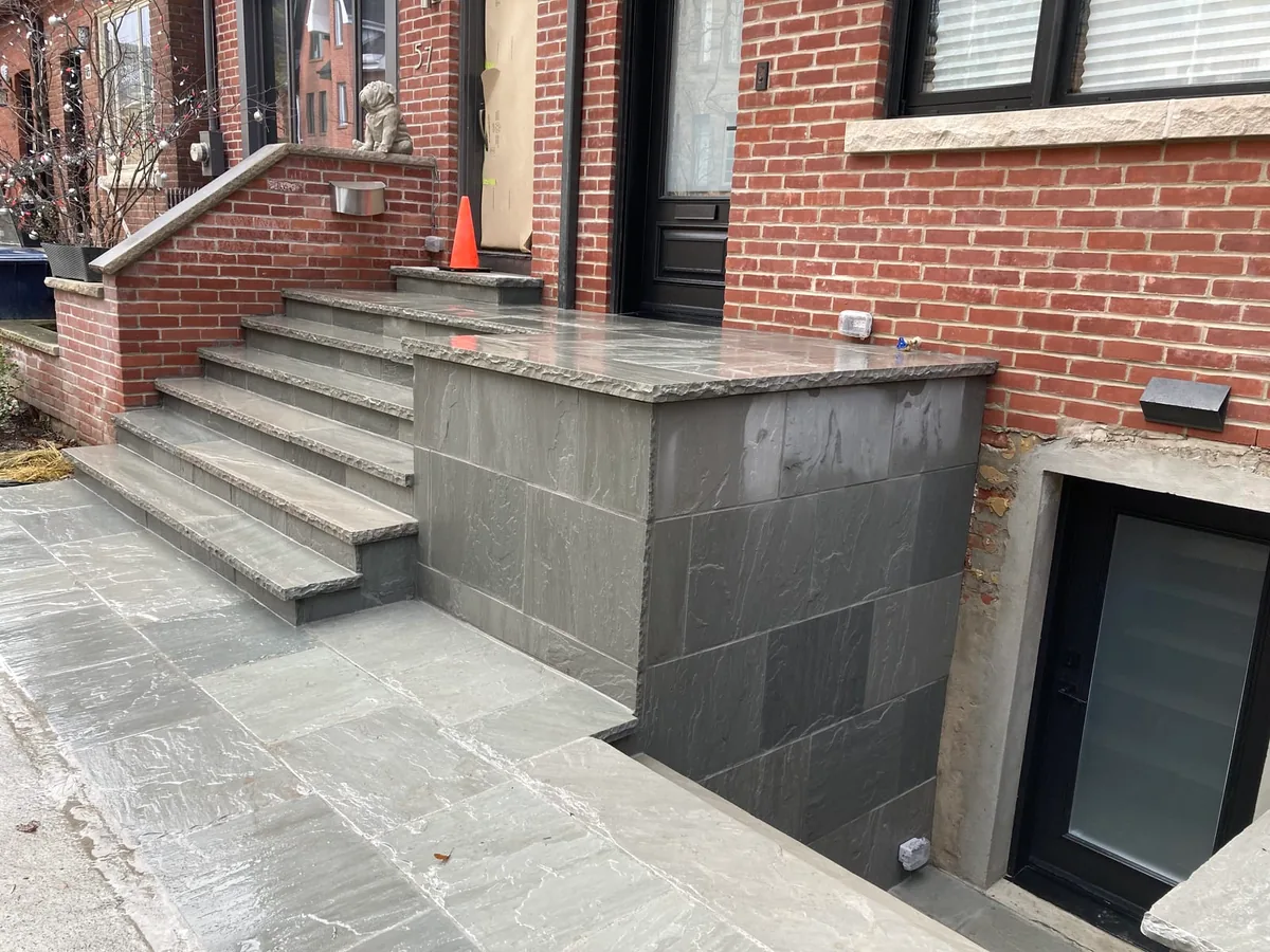 Stairwell steps down beside the coping wall, with cones and a gas meter.