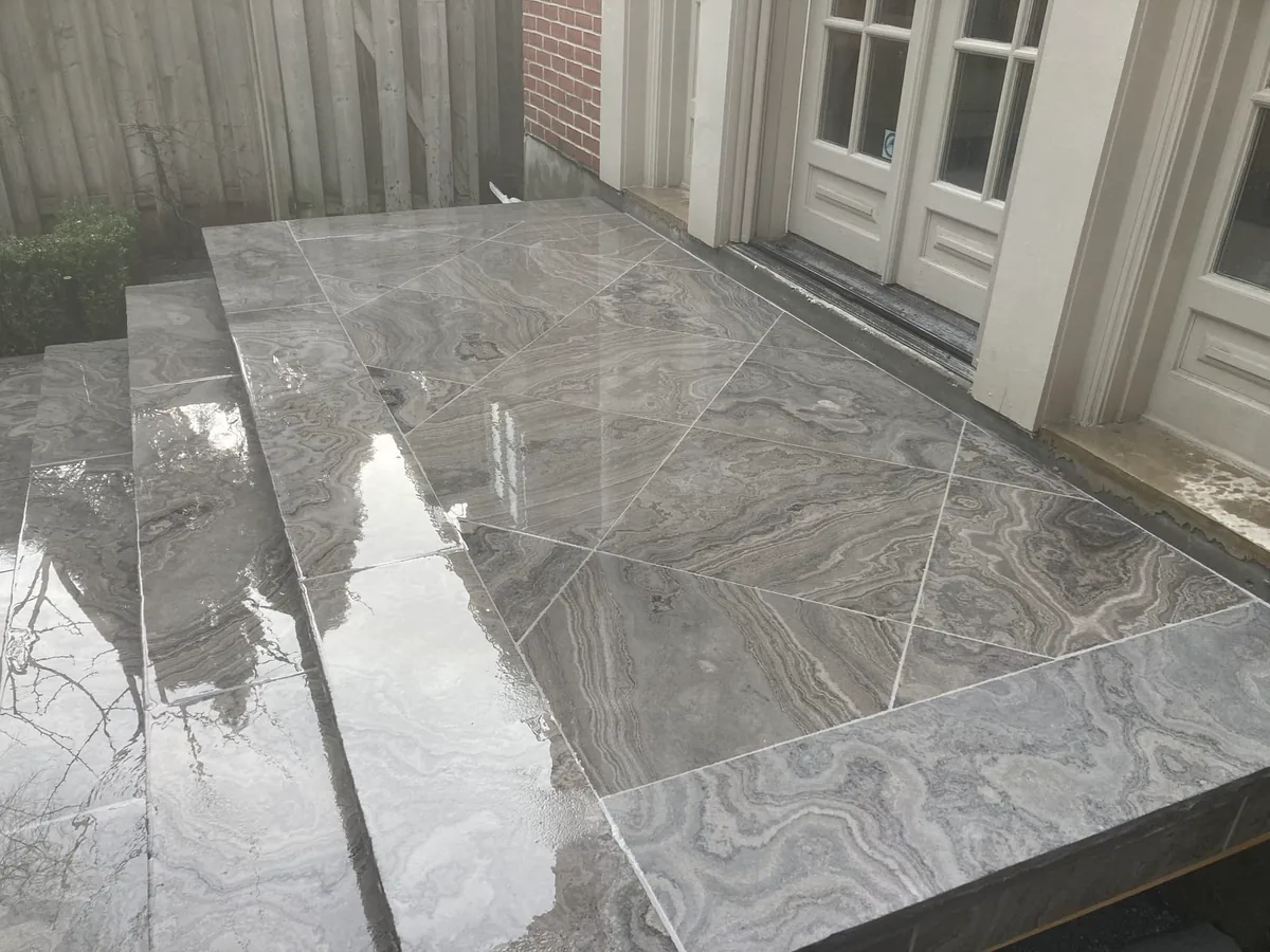 The diagonal-pattern marble patio near the steps, with a wine bottle resting on the ledge.