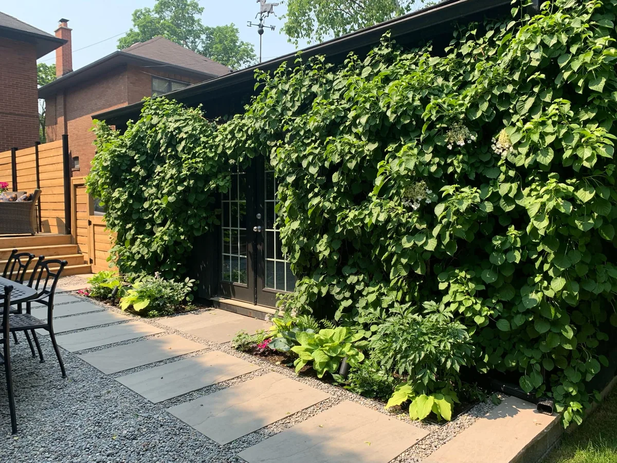 A gravel walkway with a dining table and chairs, hostas, and a deck with a hot tub beyond.