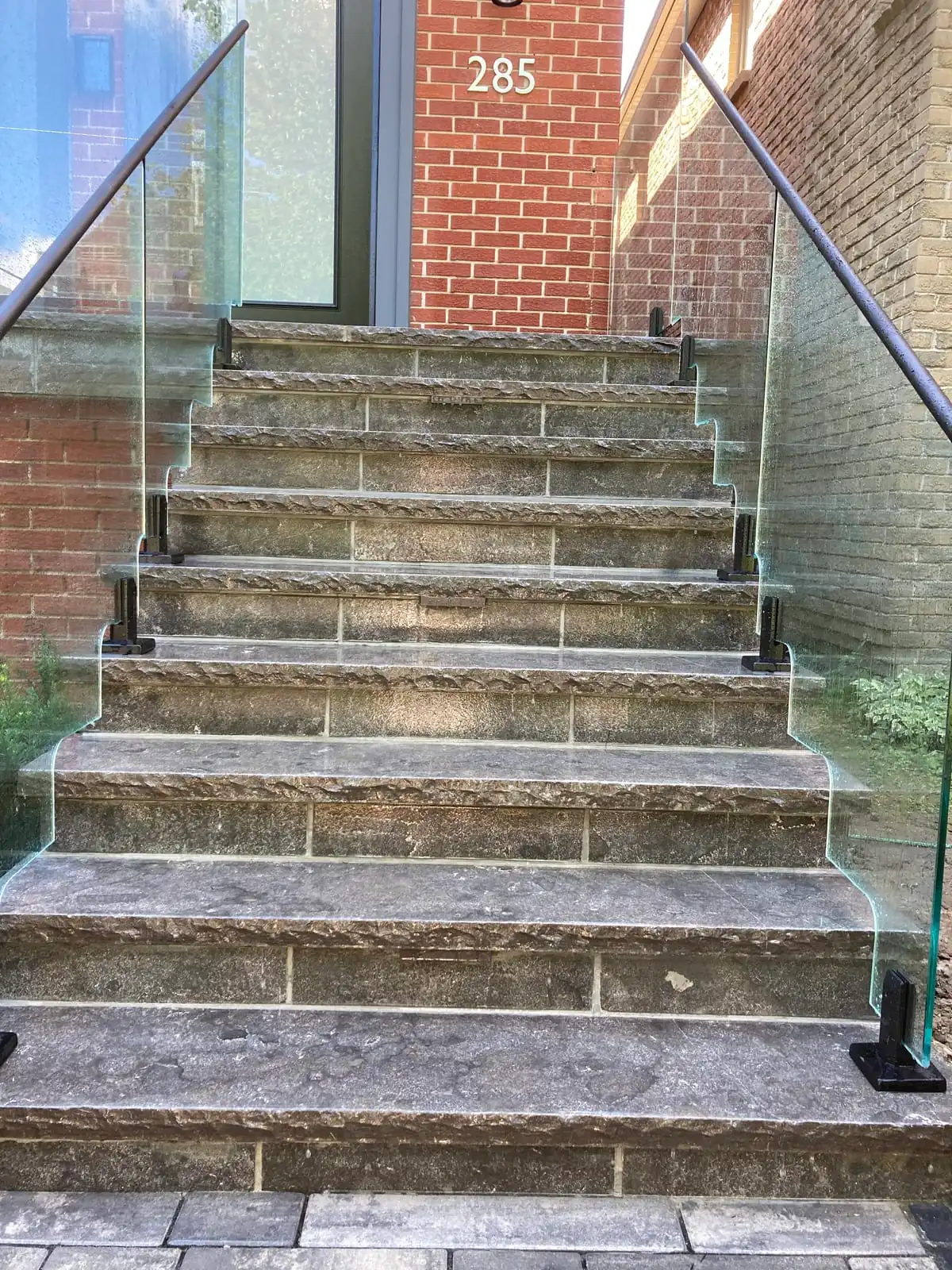 A centered upward view of the same stone steps with glass railings on both sides.