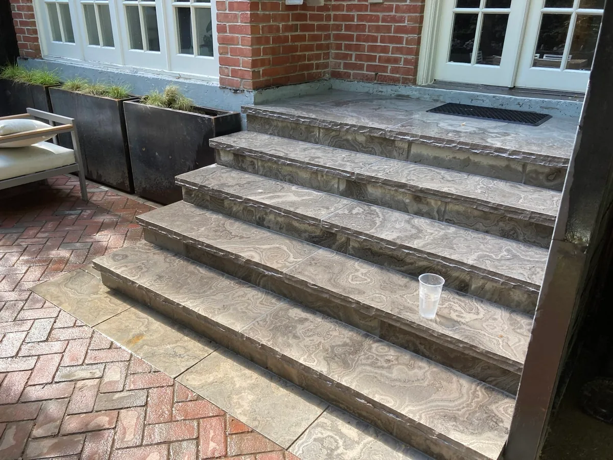 A closer view of the marble-look steps with planters nearby.